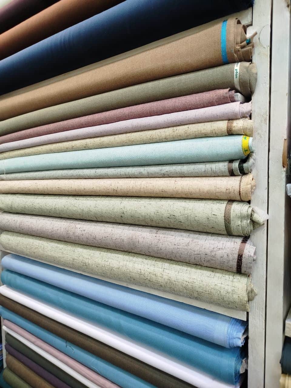 Rolls of cotton and linen in sky blue, sand, grey and pink at Shahzad Cloth House