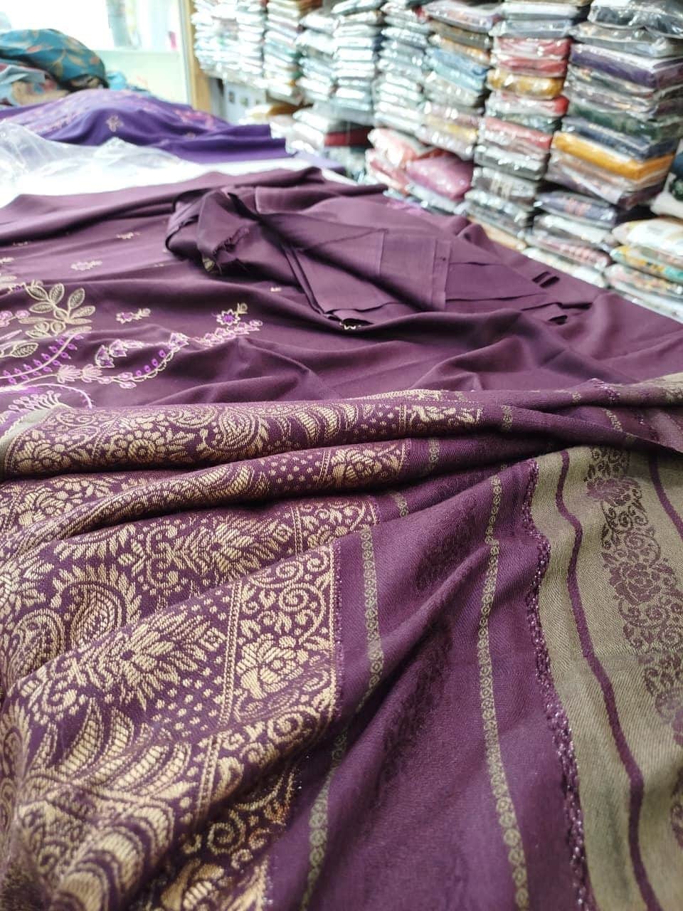 Purple jacquard fabric with a woven gold pattern, spread out at Shahzad Cloth House