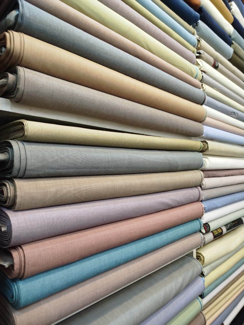Close-up of folded gents suiting in grey, green, blue and brown at Shahzad Cloth House