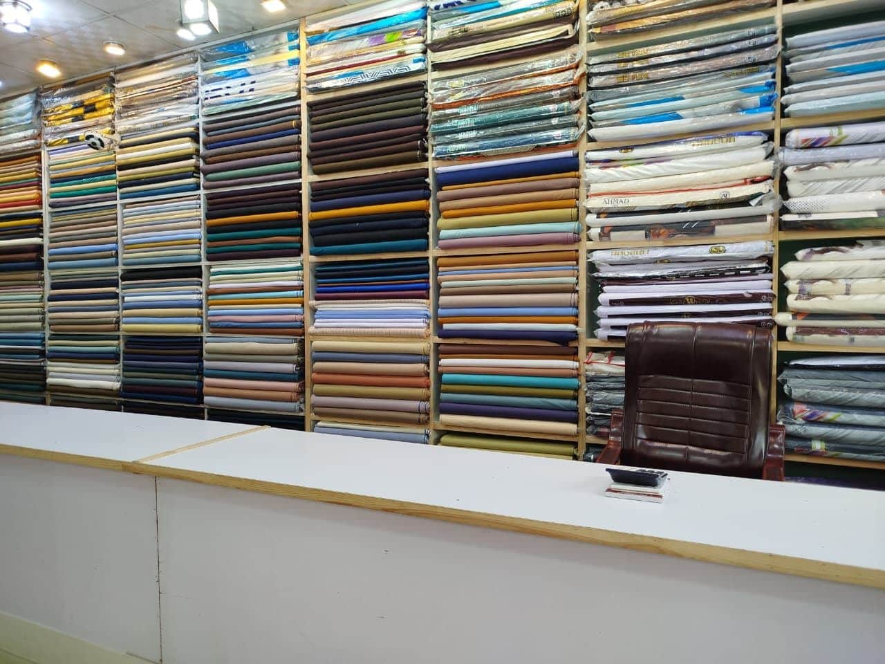 Floor-to-ceiling shelves of suiting behind the counter at Shahzad Cloth House