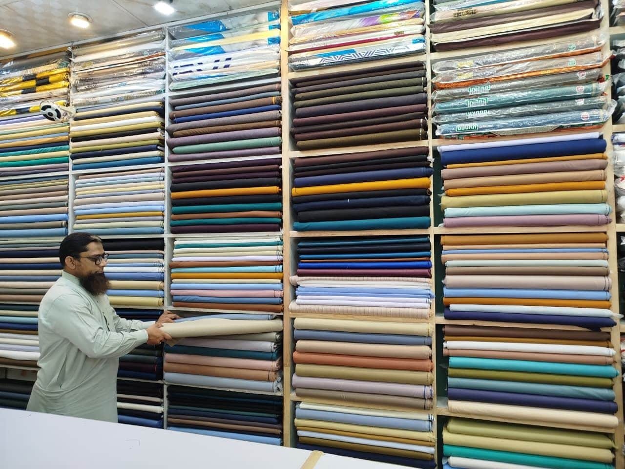 Pulling a thaan of suiting from the shelves at Shahzad Cloth House