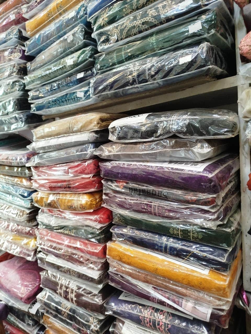 Packed unstitched suits in green, pink, purple and gold at Shahzad Cloth House