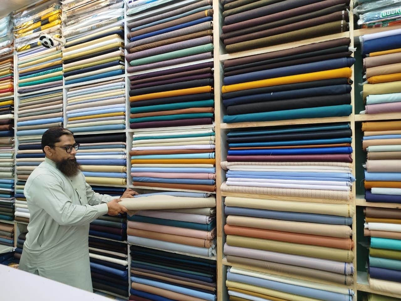 Taking a thaan down from the suiting shelves at Shahzad Cloth House